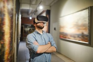 Waist up portrait of modern man wearing VR headset during virtual tour in art gallery or museum, copy space